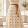 Cream crochet midi dress with oval eyelet lace pattern and caramel waist tie displayed on a white mannequin in a bright room