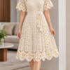 Ivory crochet mesh dress with V-neck, short sleeves, waist tie, and daisy flower appliques along the hem and cuffs