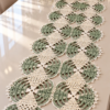 Sage green and pearl white crocheted lace table runner with circular medallions and diamond overlays displayed on a dining table