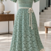 Seafoam green crochet midi dress with shell stitch pattern, ivory hem border, and slim tie belt displayed on dress form